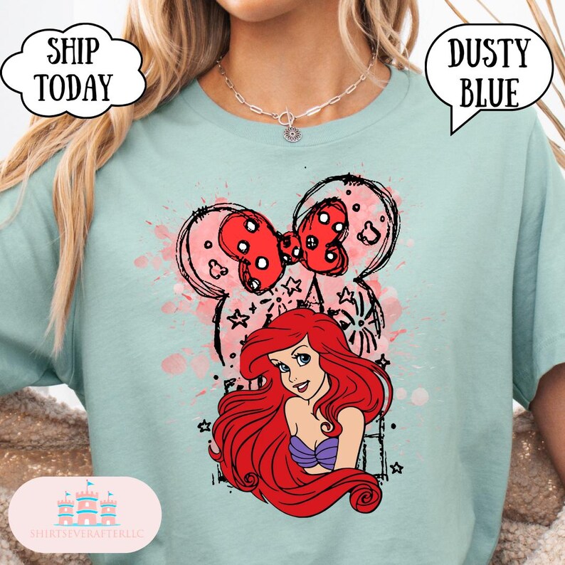 May include: Dusty blue t-shirt featuring a graphic of Ariel from The Little Mermaid, with a red bow and Mickey Mouse ears design. The shirt also has the text "Dusty Blue" in a speech bubble.