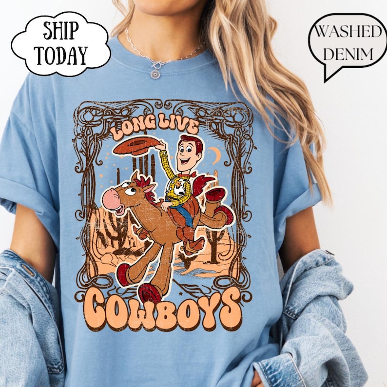 May include: Light blue t-shirt featuring a cartoon cowboy riding a horse, with the words "LONG LIVE COWBOYS" in a vintage style. The shirt has a distressed look and the text "SHIP TODAY" is in a cloud-shaped bubble.