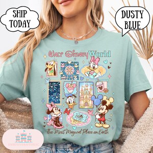 Puede incluir: Camiseta azul polvoriento con un dise&ntilde;o colorido de Walt Disney World con varios personajes y atracciones. La camiseta incluye el texto "Walt Disney World" y "The Most Magical Place on Earth".