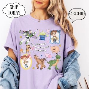 Puede incluir: Una camiseta de color morado claro con un estampado gr&aacute;fico de varios personajes animados, incluyendo un ranger espacial, un vaquero, una vaquera, un alien&iacute;gena verde, un cerdo, un caballo y un dinosaurio, con el texto "YOU'VE GOT A FRIEND IN ME".