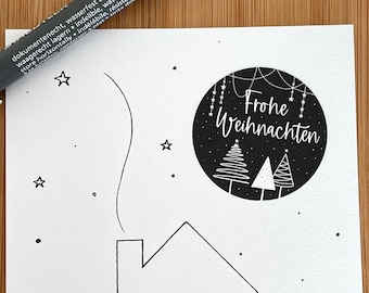 Puede incluir: Una tarjeta de Navidad imprimible en blanco y negro con una casa con un corazón en la fachada y un círculo con el texto "Frohe Weihnachten" en la esquina superior derecha.