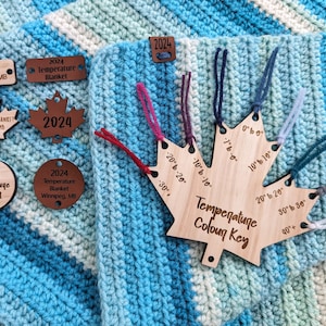 Puede incluir: Una llave de madera en forma de hoja de arce con una escala de temperatura y muestras de color. La llave está etiquetada como "Temperature Colour Key" y tiene marcas para 0° a 40°+ grados. Los colores son rojo, morado, azul, azul claro, verde azulado y gris.