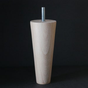 May include: A wooden furniture leg with a tapered design and a metal screw at the top.