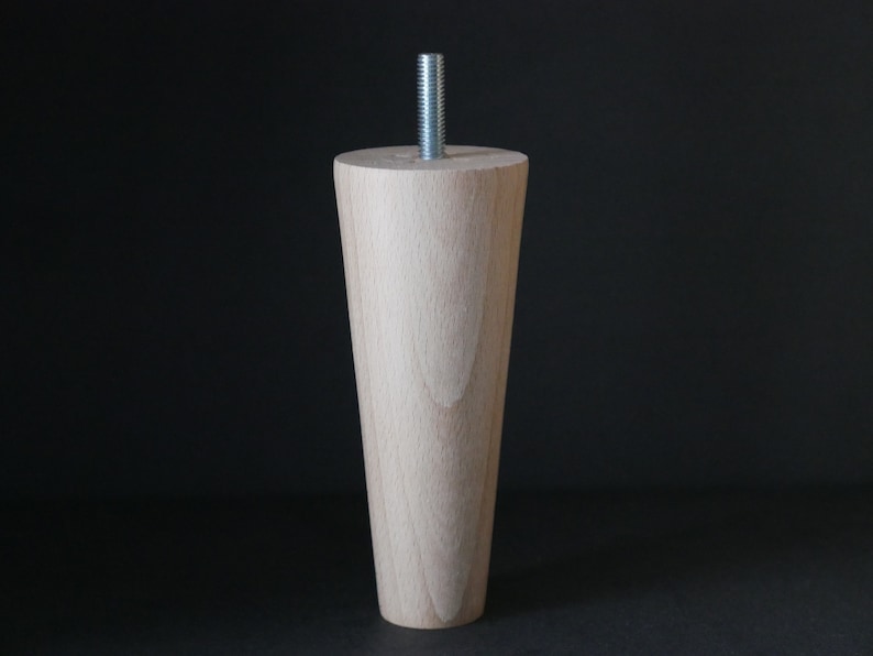 May include: A wooden furniture leg with a tapered design and a metal screw at the top.