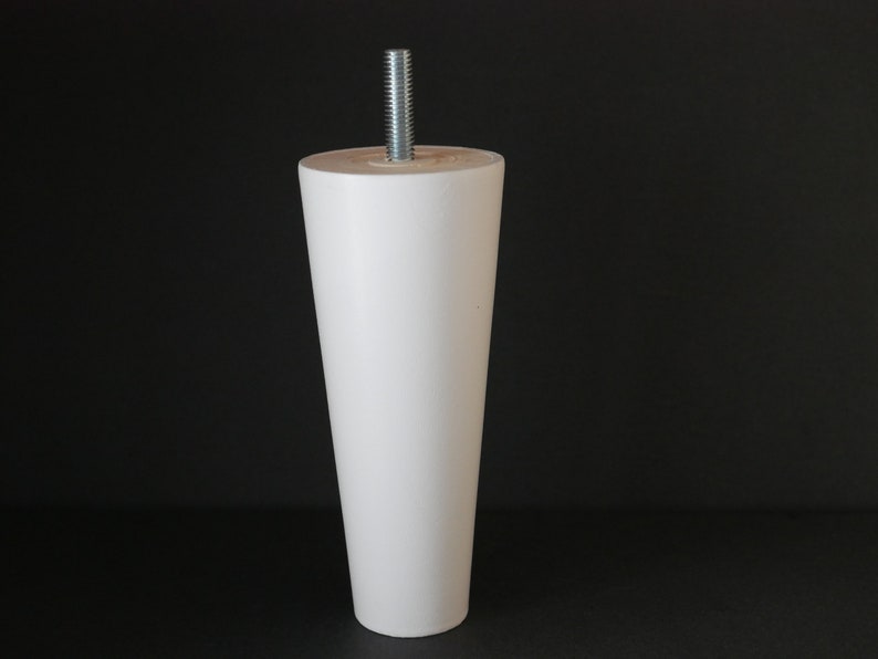 May include: White wooden furniture leg with a metal screw. The leg is tapered and has a smooth finish.