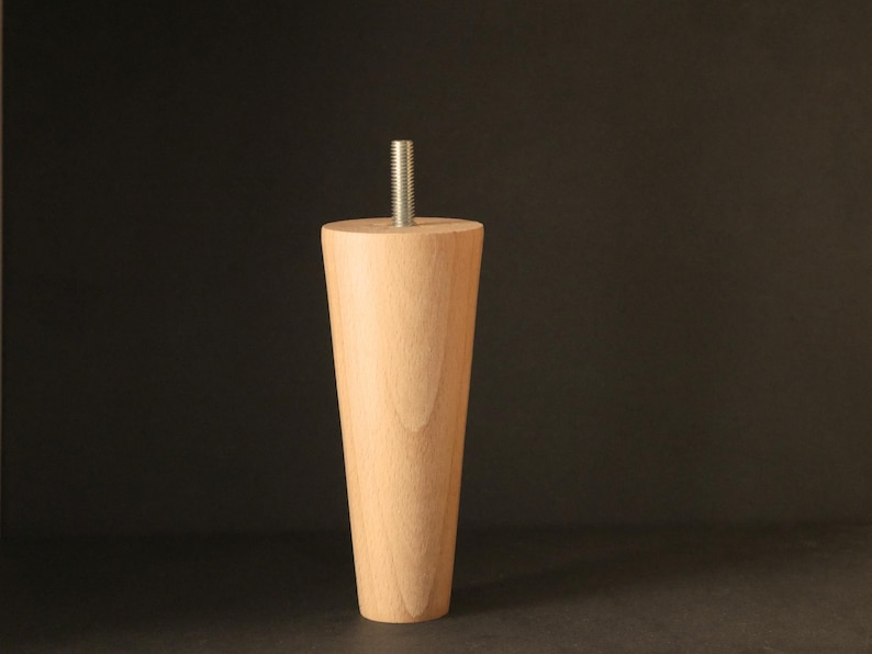 May include: A wooden furniture leg with a tapered design and a metal screw at the top.