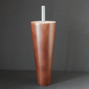 May include: A dark brown wooden furniture leg with a silver metal screw. The leg is tapered and has a smooth finish.