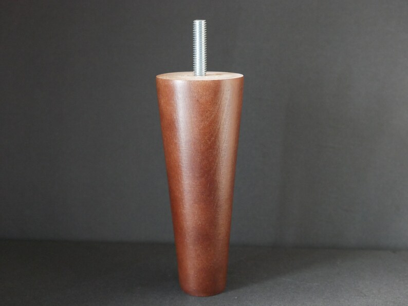 May include: A dark brown wooden furniture leg with a silver metal screw. The leg is tapered and has a smooth finish.