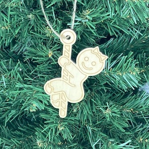 May include: A small artificial Christmas tree decorated with a wooden gingerbread man ornament hanging from a twine string.