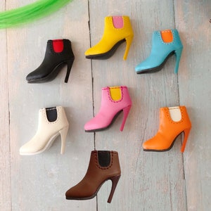 May include: Set of seven miniature ankle boots in various colors, including black, white, yellow, pink, orange, brown, and blue. Each boot has a contrasting colored trim around the top and a black heel.