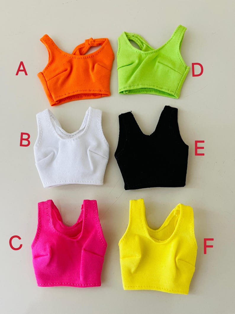 May include: Six sleeveless crop tops in various colors labeled A through F. The tops are orange, white, black, neon green, hot pink, and yellow. Each top features a scoop neckline, ribbed texture, and stitched bust detailing on the front.