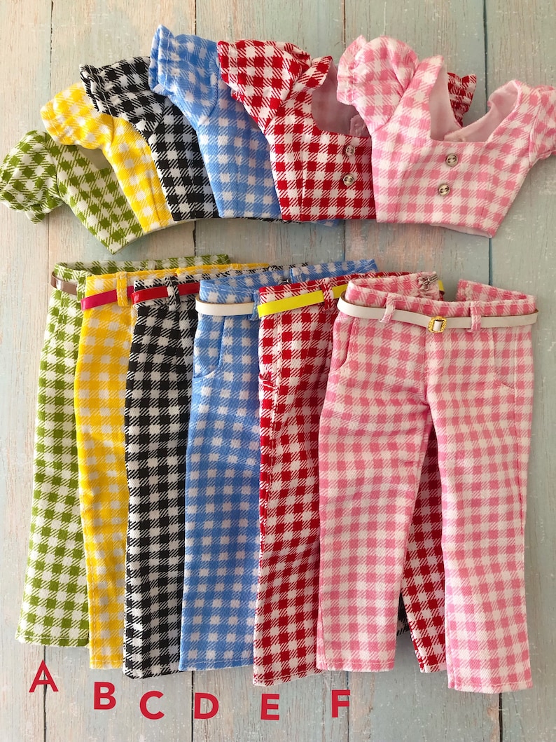 May include: Six sets of doll clothing featuring a gingham pattern in green, yellow, black, blue, red, and pink. Each set includes a short-sleeved crop top with two buttons and matching trousers with a thin belt. The sets are labeled A through F.