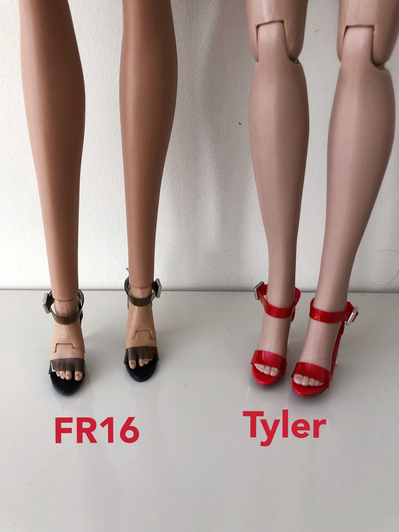 Op de afbeelding: Twee paar sandalen met hoge hakken. Het eerste paar is zwart met doorzichtige banden en het tweede paar is rood. De sandalen zijn gelabeld met "FR16" en "Tyler".