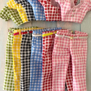May include: A collection of six doll outfits, each consisting of a short-sleeved blouse and matching trousers in a gingham check pattern. The sets come in green, yellow, black, blue, red, and pink, with each pair of trousers featuring a thin belt.