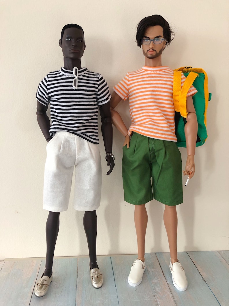 Puede incluir: Dos mu&ntilde;ecos de moda de pie uno al lado del otro. El mu&ntilde;eco de la izquierda lleva una camiseta a rayas blancas y negras, pantalones cortos blancos y mocasines plateados. El de la derecha lleva una camiseta a rayas naranjas y blancas, pantalones cortos verdes, zapatos blancos y una mochila verde.