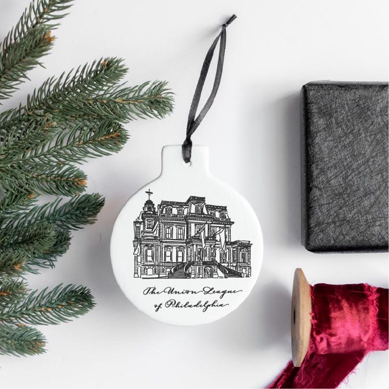 May include: White ceramic Christmas ornament with a black and white illustration of a building and the text "The Union League of Philadelphia".