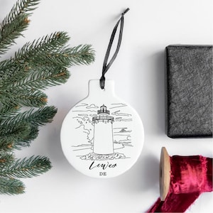 Peut inclure: Ornement de No&euml;l en c&eacute;ramique blanche avec un dessin au trait noir et blanc d'un phare et le texte "Lewes DE".