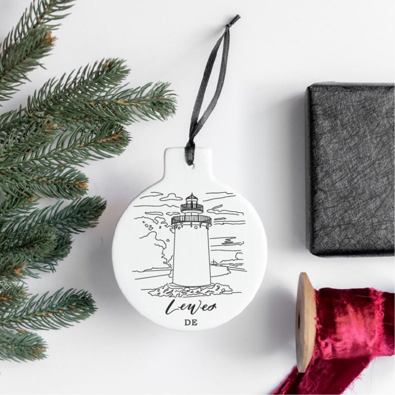 Peut inclure: Ornement de No&euml;l en c&eacute;ramique blanche avec un dessin au trait noir et blanc d'un phare et le texte "Lewes DE".