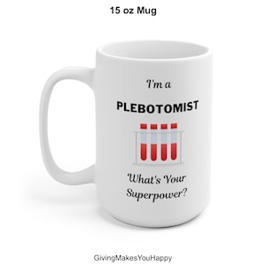 May include: White 15 oz mug with the text "I'm a PLEBOTOMIST, What's Your Superpower?" and a graphic of four test tubes with red liquid. The mug has a curved handle and is suitable for hot or cold beverages.