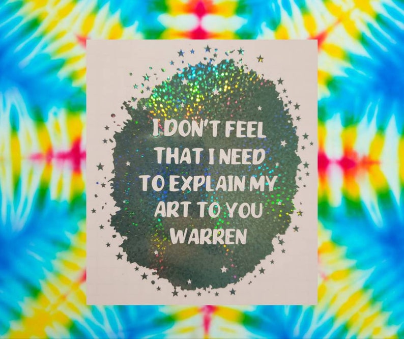 May include: A holographic sticker with a black circle and white stars. The text inside the circle reads "I don't feel that I need to explain my art to you Warren".