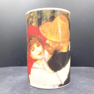 Peut inclure: Mug cylindrique en céramique avec une image vintage d'un couple dans une étreinte romantique. La femme porte un couvre-chef rouge. L'homme porte un chapeau. La tasse a un bord et une base blancs.