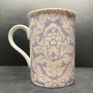 May include: A white ceramic mug with a purple and white damask pattern.