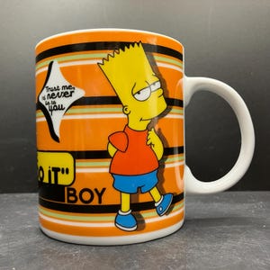 May include: A white ceramic mug featuring Bart Simpson from The Simpsons cartoon. The mug has an orange background with black and green stripes. Bart is wearing an orange shirt, blue shorts, and blue shoes. Text on the mug includes "Trust me, I'd never lie to you" and "Do it" BOY.