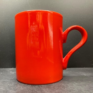 Peut inclure: Une tasse en céramique rouge vif avec une anse incurvée. La tasse a une finition brillante et une forme cylindrique. La poignée est fixée sur le côté de la tasse, offrant une prise en main confortable. Convient aux boissons chaudes ou froides.
