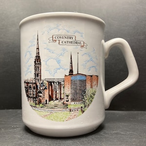 May include: White ceramic mug with a colorful illustration of Coventry Cathedral. The mug has a handle and the text "COVENTRY CATHEDRAL" is printed on the front.
