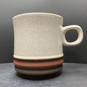 以下が含まれることがあります： 茶色と濃い茶色の縞模様のベースと丸みを帯びたハンドルが付いた、斑点のあるベージュのセラミックマグ。 マグカップは円筒形で、コーヒーや紅茶に適したシンプルでクラシックなデザインです。