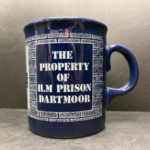 May include: A blue ceramic mug with a white design that says "The Property of H.M. Prison Dartmoor".