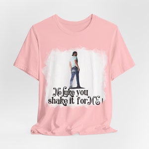 May include: Pink t-shirt with a white graphic of a man in jeans and a white shirt. The graphic has the text "No like you shake it for ME!" printed below it.