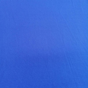 Op de afbeelding: Een effen blauwe stofstaal. De stof heeft een gladde, gelijkmatige textuur.