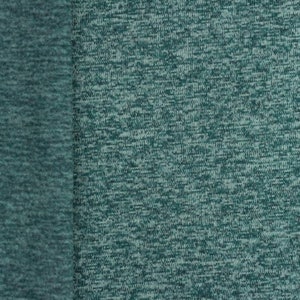 Op de afbeelding: Close-up van een teal stof met een textuur, gespikkeld patroon. De stof voelt glad en zacht aan.