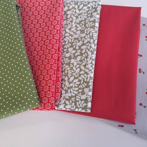 Peut inclure: Cinq échantillons de tissu dans différents motifs et couleurs. Les échantillons sont verts à pois blancs, rouges à imprimé floral blanc, blancs à imprimé floral vert, rouge uni et gris à cerises rouges.