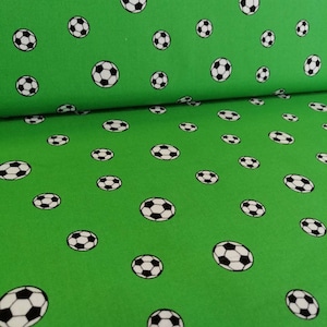 Op de afbeelding: Groene stof met een herhalend patroon van witte en zwarte voetballen.