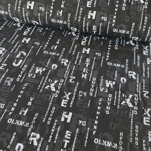 Può includere: Tessuto nero con un motivo ripetitivo di lettere bianche in uno stile grunge e usurato. Le lettere sono di diverse dimensioni e orientamenti.