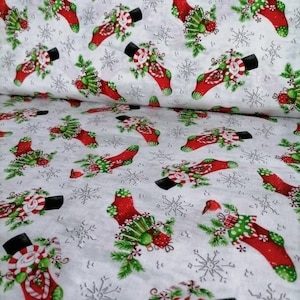 Könnte beinhalten: Weißer Stoff mit einem sich wiederholenden Muster aus roten Weihnachtsstrümpfen, die jeweils mit grünen Akzenten, Zuckerstangen und einem Schneemann verziert sind. Graue Schneeflocken sind im Hintergrund verstreut.