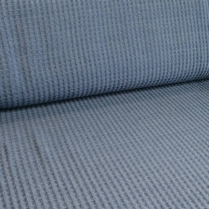 Könnte beinhalten: Nahaufnahme eines blauen Waffelstrickstoffs. Der Stoff hat ein strukturiertes, waffelartiges Muster und ein weiches, angenehmes Gefühl.