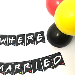 May include: Black and white banner with the text "We Were Married" in a white font. The banner is decorated with colorful dots. The banner is hanging from a string. There are balloons in the background.