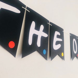 May include: Black and white banner with the words "THE ONE" in white letters. The banner has red, blue, and yellow dots on each flag.