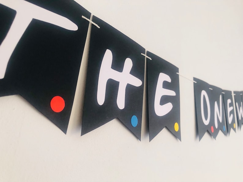 May include: Black and white banner with the words "THE ONE" in white letters. The banner has red, blue, and yellow dots on each flag.