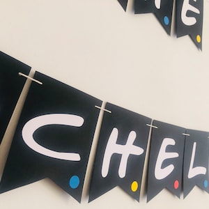 May include: Black and white banner with the words "Friends" in white letters on black triangles. Each triangle has a small colored dot in the corner. The colors are red, yellow, and blue.