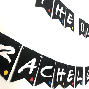May include: Black and white banner with the text "The One Where Rachel Gets Married" in a white font. The banner is decorated with colorful dots.
