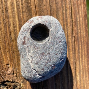 May include: A grey stone with a round hole in the centre. The hole is lined with a metal mesh.