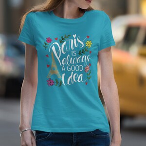 May include: A turquoise blue t-shirt with a white graphic print of the Eiffel Tower and the text "Paris is always a good idea" surrounded by flowers and hearts.