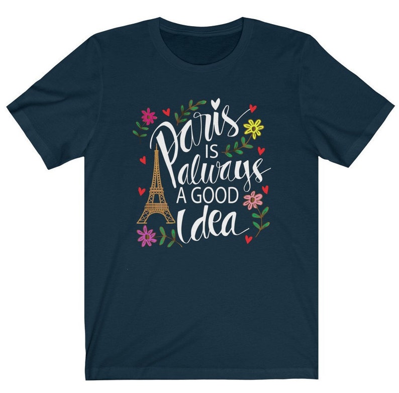 May include: A navy blue t-shirt with a white graphic design featuring the Eiffel Tower and the text "Paris is always a good idea" surrounded by flowers.