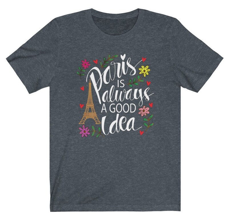 May include: A dark heather grey t-shirt with a white graphic design featuring the Eiffel Tower and the text "Paris is always a good idea". The graphic is surrounded by colorful flowers and hearts.
