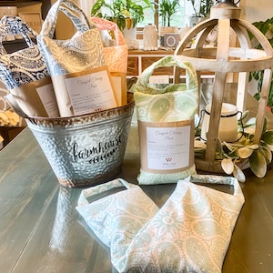 May include: Four green and white paisley patterned fabric heat packs with the text "Comfort Therapy Pack" and "White Camel" on the packaging. The heat packs are in a metal bucket with the word "farmhouse" on the side.