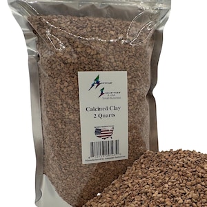 May include: A clear plastic bag filled with calcined clay, labeled "Awesome Industries A USA Small Business." The label reads "Calcined Clay 2 Quarts." A pile of the clay is in front of the bag. The clay is a light brown color.